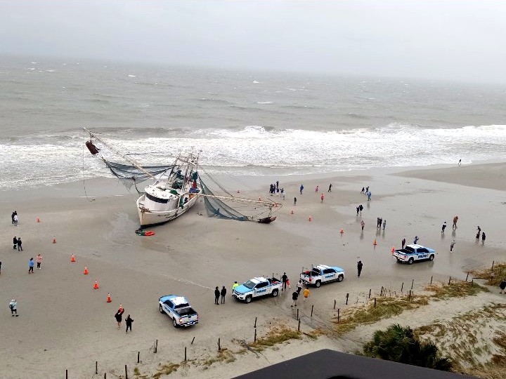 The Shayne Michelle beached on the sand at Myrtle Beach, ringed with orange cones, police vehicles, and onlookers